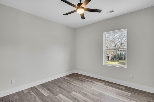 empty room with a ceiling fan, visible vents, light wood finished floors, and baseboards