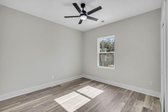 spare room with light wood finished floors, baseboards, visible vents, and a ceiling fan