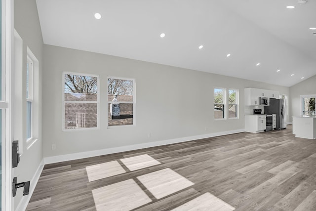 unfurnished living room featuring recessed lighting, vaulted ceiling, light wood-style flooring, and baseboards