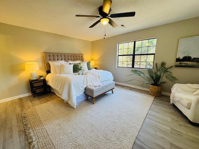 bedroom with a textured ceiling, light hardwood / wood-style floors, and ceiling fan