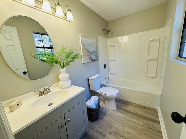 full bathroom with vanity, bathing tub / shower combination, hardwood / wood-style flooring, toilet, and a textured ceiling