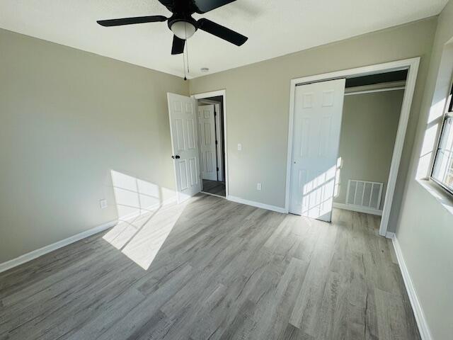 unfurnished bedroom with a closet, light hardwood / wood-style flooring, and ceiling fan