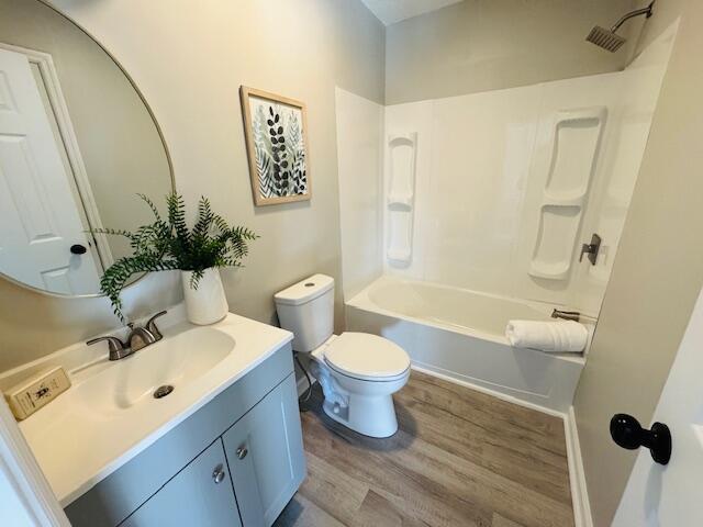 full bathroom featuring bathtub / shower combination, vanity, hardwood / wood-style flooring, and toilet