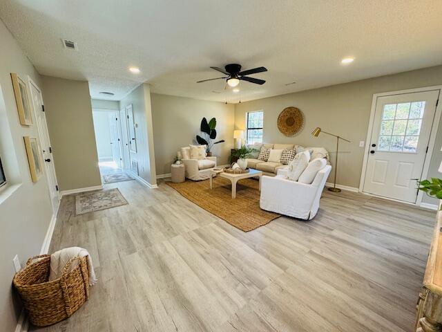 living room with a wealth of natural light, a textured ceiling, light hardwood / wood-style flooring, and ceiling fan