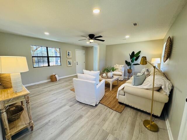 living room featuring ceiling fan and light hardwood / wood-style floors