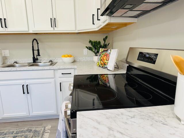 kitchen featuring range with electric stovetop, sink, white cabinets, and exhaust hood