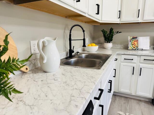 kitchen with white cabinets, light wood-type flooring, and sink