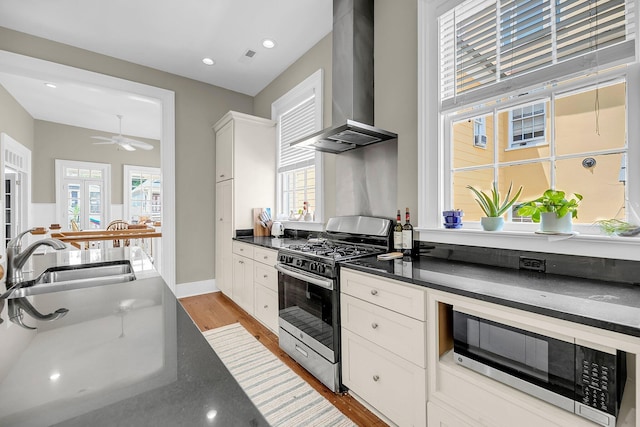 68 Vanderhorst St Unit B, Charleston, SC 29403 - kitchen with stainless steel appliances, wall chimney exhaust hood, dark countertops, light wood-style flooring, and white cabinets