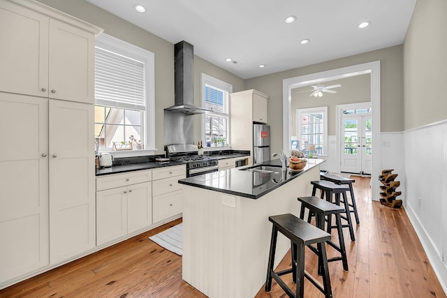 68 Vanderhorst St Unit B, Charleston, SC 29403 - kitchen featuring appliances with stainless steel finishes, wall chimney exhaust hood, a kitchen breakfast bar, dark countertops, and an island with sink