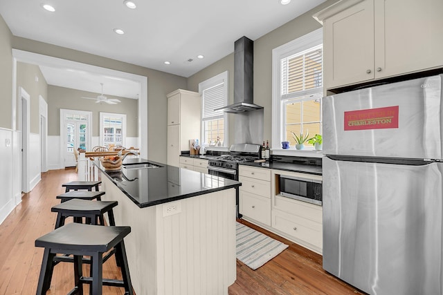 68 Vanderhorst St Unit B, Charleston, SC 29403 - kitchen with appliances with stainless steel finishes, wall chimney exhaust hood, dark countertops, light wood-type flooring, and recessed lighting