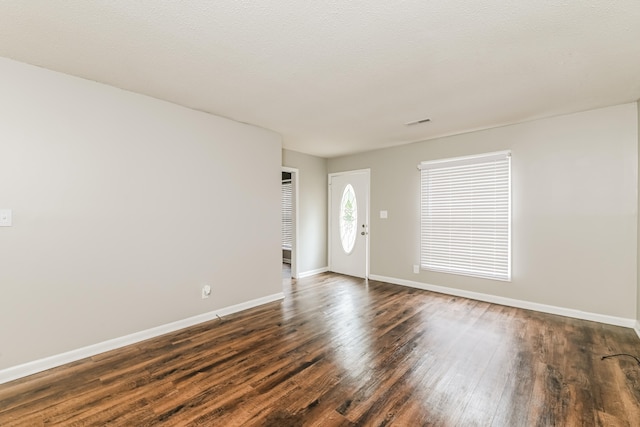 unfurnished room with a textured ceiling and dark wood-type flooring