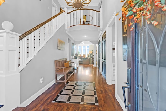 foyer featuring crown molding, dark wood-type flooring, a chandelier, and a towering ceiling