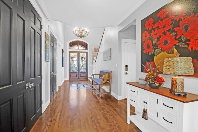 entryway with ornamental molding, dark wood-type flooring, a notable chandelier, and french doors