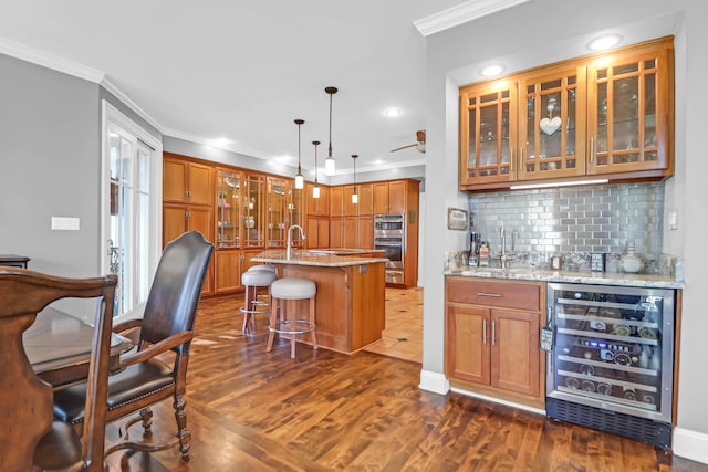 bar featuring pendant lighting, beverage cooler, light stone countertops, and crown molding