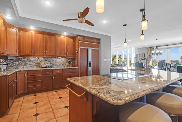 kitchen with pendant lighting, a kitchen bar, paneled fridge, and a large island with sink