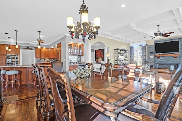 dining room featuring dark hardwood / wood-style floors, a fireplace, coffered ceiling, and ceiling fan with notable chandelier