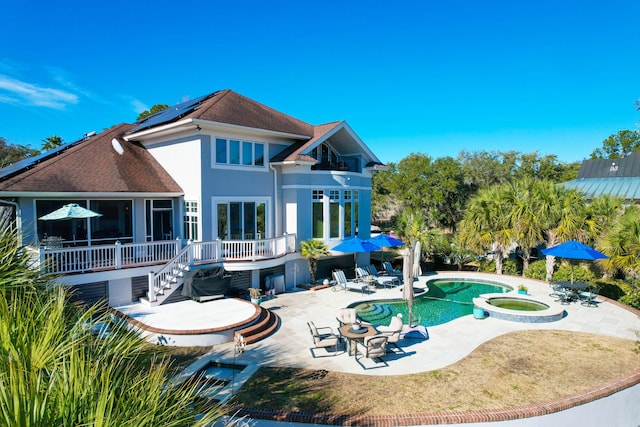 back of house with a pool with hot tub, a patio area, and solar panels