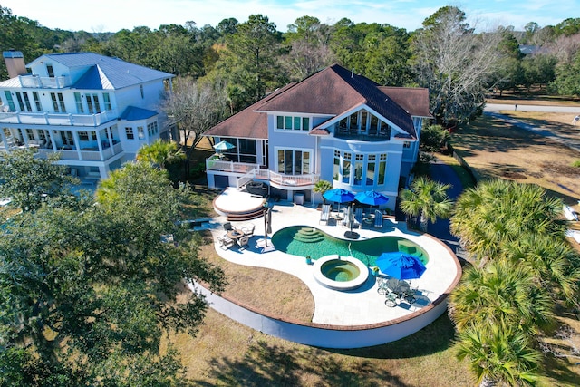 back of property featuring a swimming pool with hot tub and a patio area