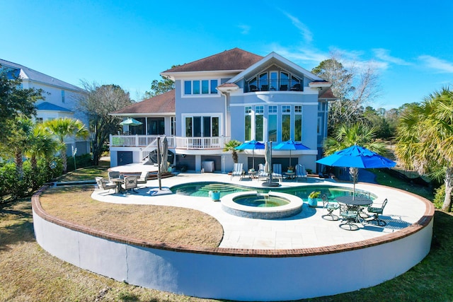 rear view of property with a pool with hot tub and a patio