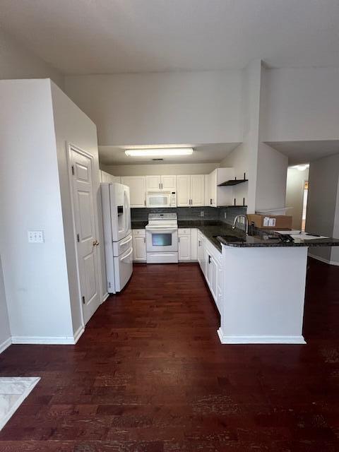 kitchen with white appliances, dark wood-type flooring, white cabinets, and kitchen peninsula