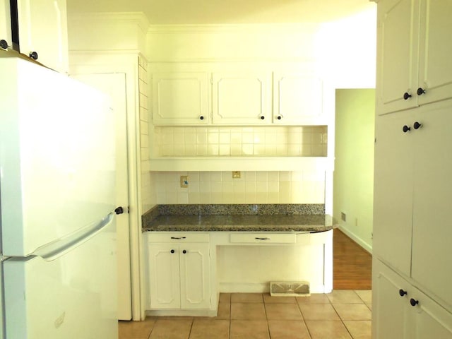 kitchen with white fridge, light tile patterned floors, and white cabinets