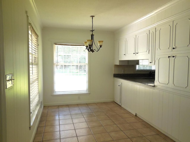 kitchen with pendant lighting, white cabinets, light tile patterned floors, ornamental molding, and a notable chandelier