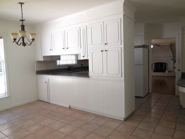 kitchen with white cabinets, white refrigerator, a fireplace, and light tile patterned flooring