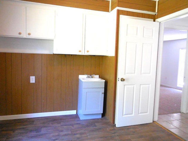 laundry area featuring sink, wood walls, and dark hardwood / wood-style flooring