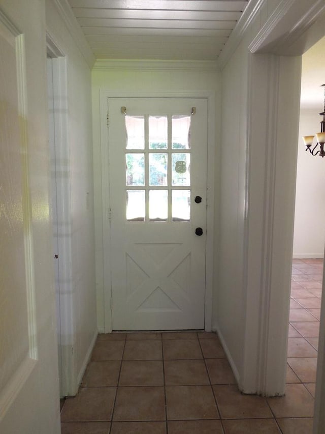 doorway to outside with dark tile patterned flooring, crown molding, and wooden ceiling