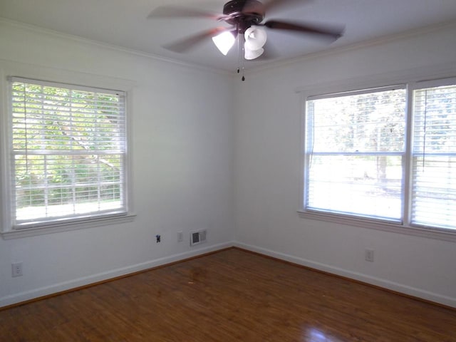 spare room featuring crown molding, a wealth of natural light, and dark wood-type flooring