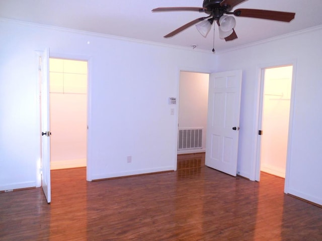 unfurnished bedroom with ceiling fan, crown molding, a spacious closet, a closet, and dark hardwood / wood-style floors