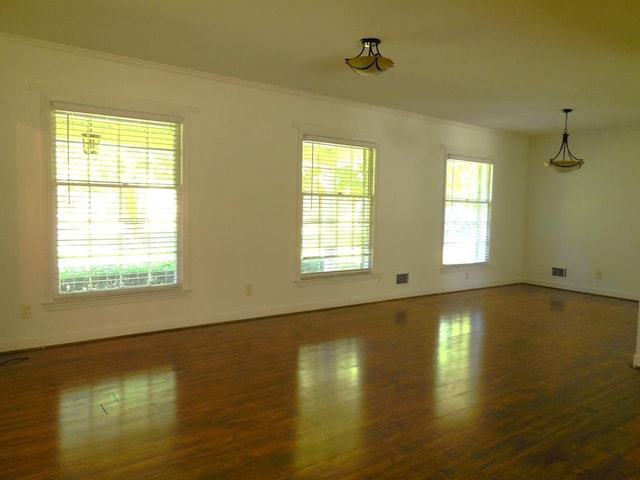 empty room with ornamental molding and dark hardwood / wood-style flooring