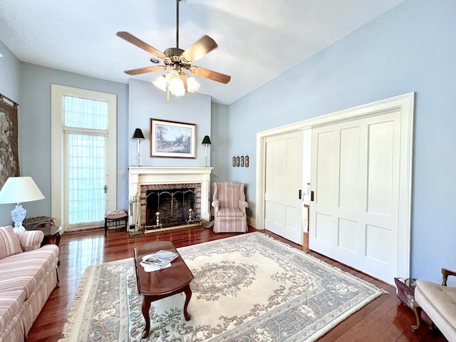 living room featuring a brick fireplace, ceiling fan, and dark hardwood / wood-style floors