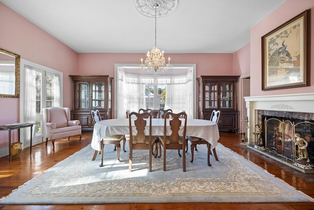 dining room featuring a tiled fireplace, dark hardwood / wood-style flooring, and an inviting chandelier