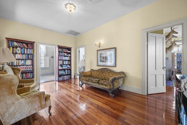 living area with a textured ceiling, a wealth of natural light, and dark hardwood / wood-style floors