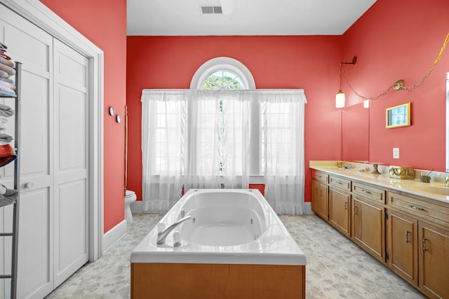 bathroom featuring toilet, vanity, and a bath