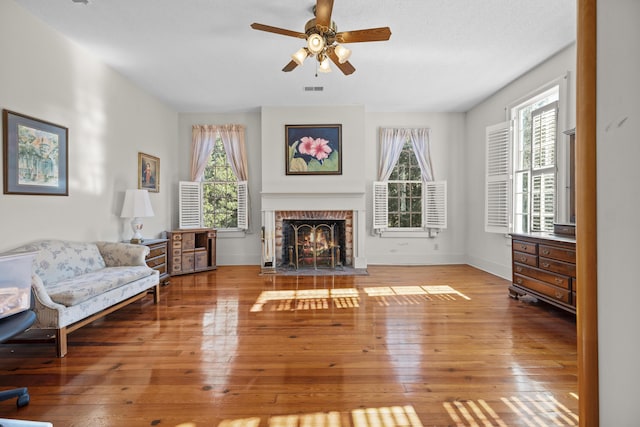 living room with ceiling fan, a fireplace, and wood-type flooring