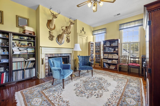 living area with a textured ceiling, ceiling fan, and dark hardwood / wood-style flooring