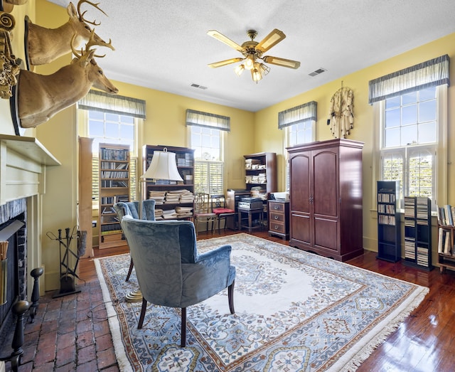 living room with a textured ceiling, ceiling fan, and dark hardwood / wood-style floors