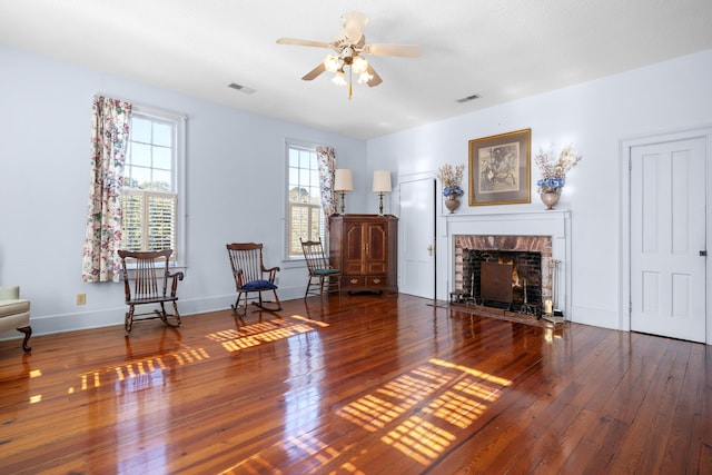 unfurnished room featuring hardwood / wood-style flooring, ceiling fan, and a fireplace