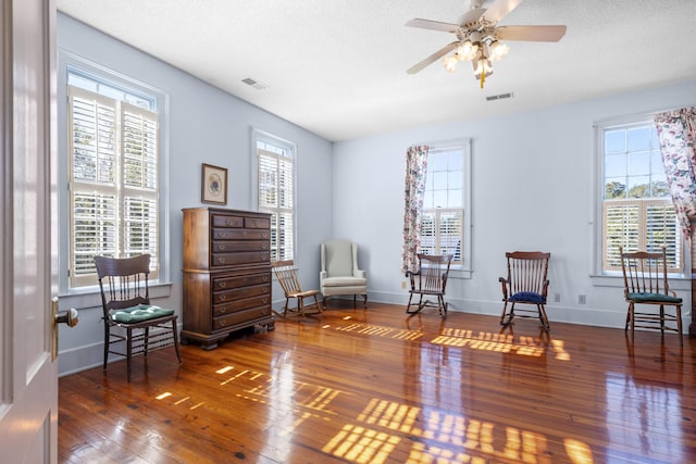 living area featuring hardwood / wood-style flooring, a textured ceiling, and ceiling fan