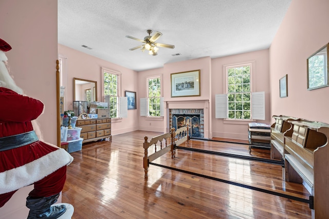 living room with a textured ceiling, a fireplace, ceiling fan, and hardwood / wood-style flooring