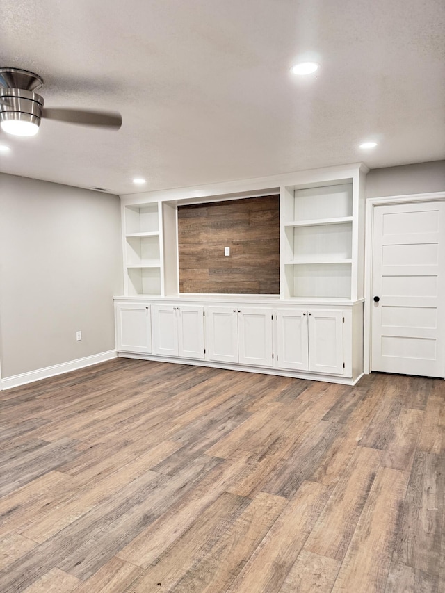 unfurnished living room with wood-type flooring, built in features, and a textured ceiling