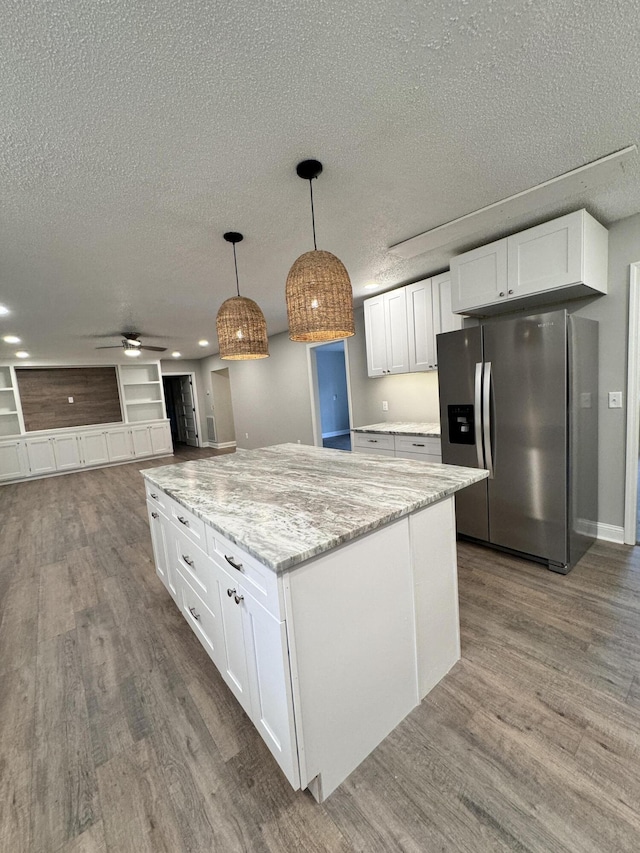 kitchen featuring pendant lighting, hardwood / wood-style floors, light stone counters, white cabinets, and stainless steel fridge with ice dispenser