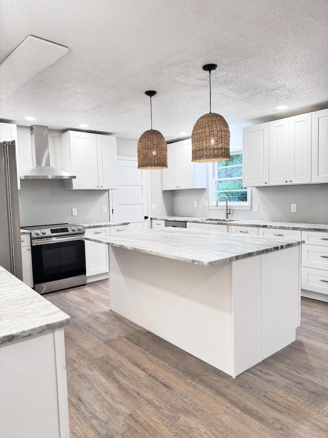 kitchen featuring white cabinets, appliances with stainless steel finishes, and wall chimney range hood