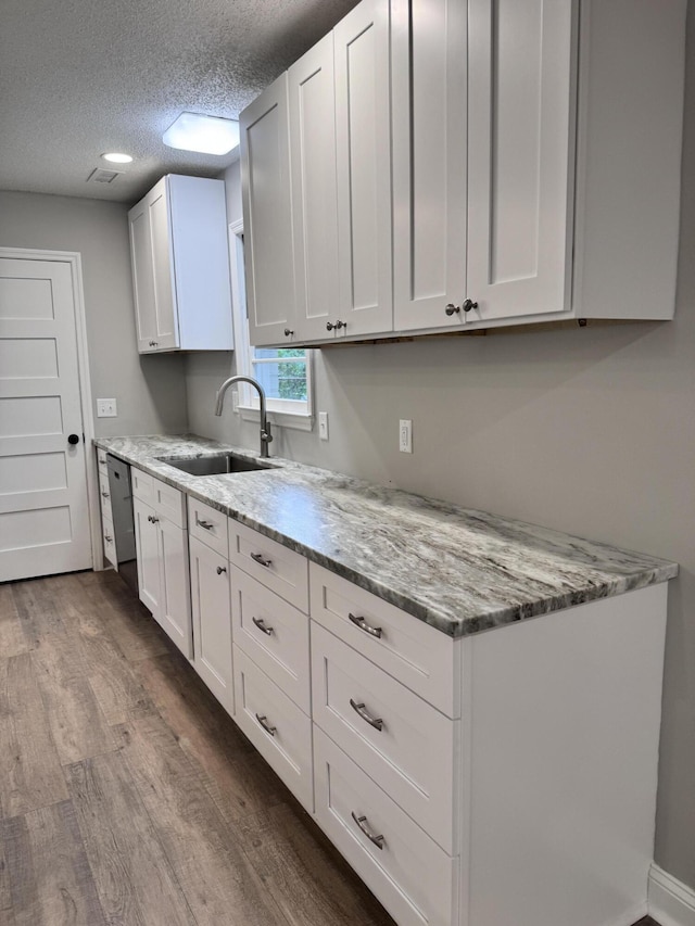 kitchen featuring sink, white cabinets, and light stone counters