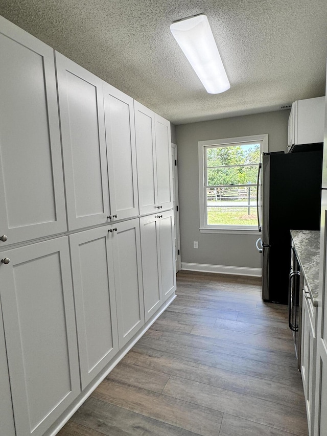 kitchen featuring stainless steel fridge, light wood-type flooring, a textured ceiling, and white cabinets