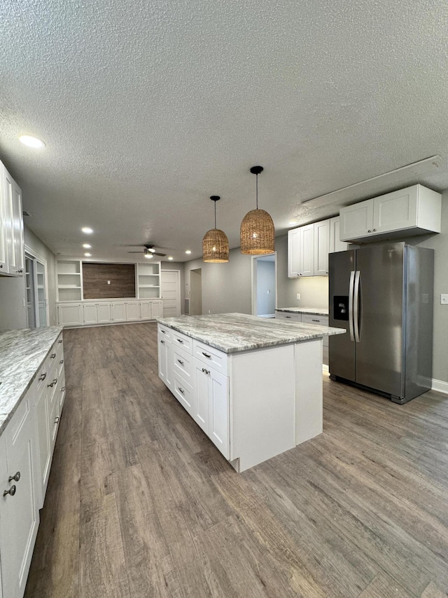 kitchen featuring a kitchen island, pendant lighting, white cabinetry, light stone counters, and stainless steel refrigerator with ice dispenser