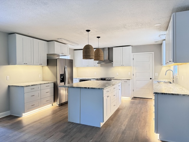 kitchen with sink, white cabinetry, hanging light fixtures, a center island, and wall chimney exhaust hood