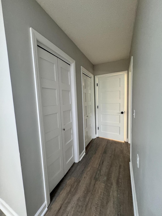 hallway featuring a textured ceiling and dark hardwood / wood-style flooring